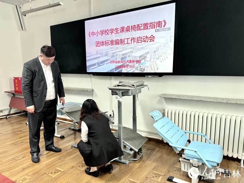 政協委員、課桌椅生產企業對市面上的課桌椅展開研究討論。人民網記者 李思玥攝