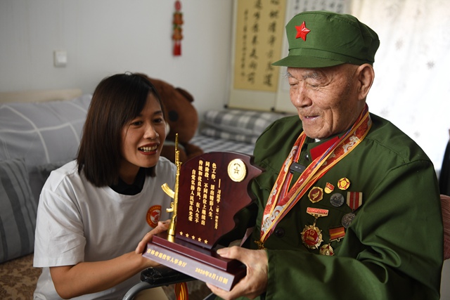 吉林省退役軍人事務廳工作人員向老兵徐洪英贈送榮譽紀念牌。