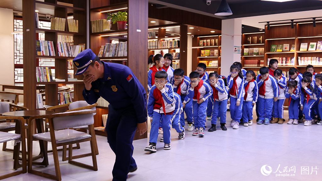 11月8日，吉林省洮南市文化廣播電視和旅游局聯合洮南市消防救援局、洮南市實驗小學深入博物館、洮南書局開展“全民消防 生命至上”主題消防安全教育活動?；顒蝇F場，消防指戰員指導小學生如何在公共場館正確疏散。人民網 李成偉攝