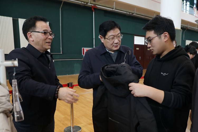 學校黨委書記盧志文為受助學生挑選棉衣并親切交談