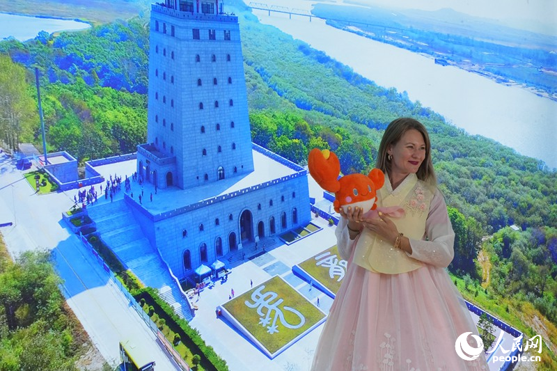 塔尼婭在延邊展館“一眼望三國”背景板前打卡拍照。人民網記者 李洋攝