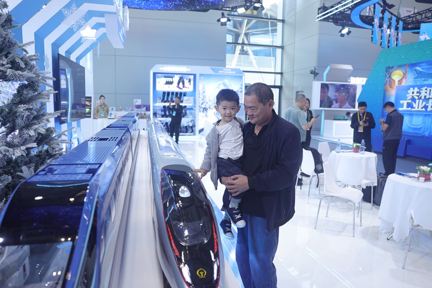 被抱起的小朋友，高興地和高鐵模型來一場“親密接觸”。人民網記者 王海躍攝